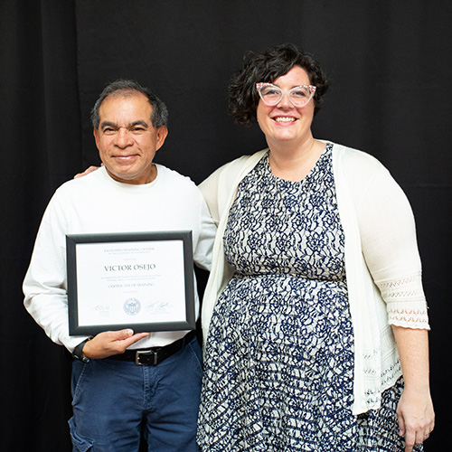 man holding a plaque next to a woman with her arms around his shoulders